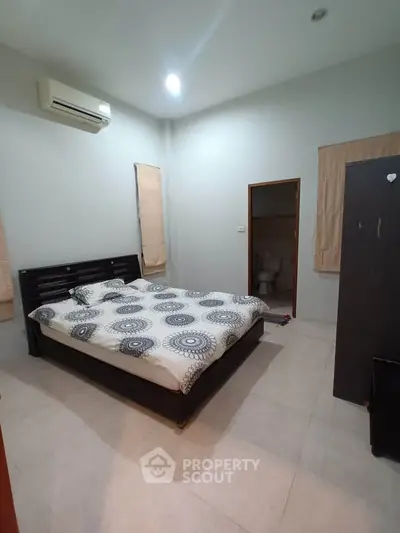 Spacious bedroom with modern decor and ensuite bathroom in a stylish apartment.