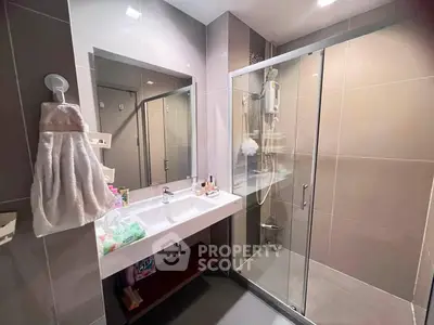 Modern bathroom with glass shower and sleek vanity in contemporary apartment.
