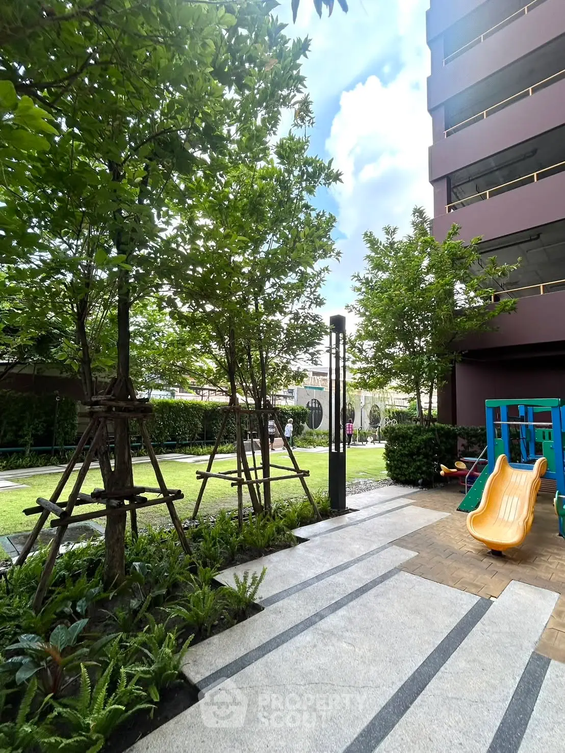 Modern residential building with lush garden and children's play area, perfect for family living.