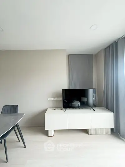 Modern living room with sleek TV stand and dining area, featuring minimalist design and neutral tones.