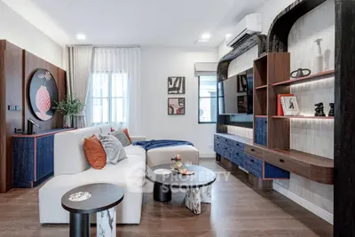 Modern living room with stylish decor, featuring a cozy sofa, elegant shelving, and contemporary art pieces.