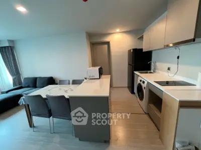 Modern open-layout kitchen and living room with sleek appliances and stylish furniture.
