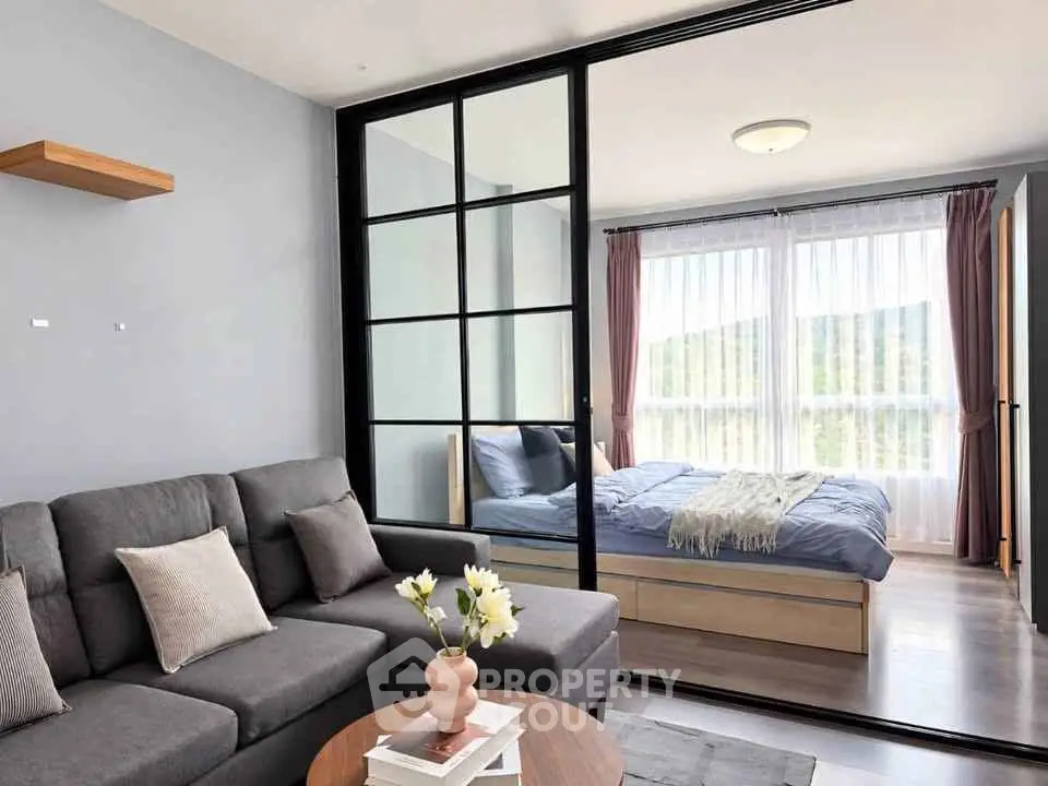 Modern living room with sliding glass doors leading to a cozy bedroom with natural light.