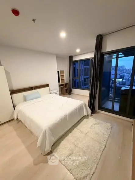 Spacious bedroom with modern decor and balcony view in a stylish apartment.