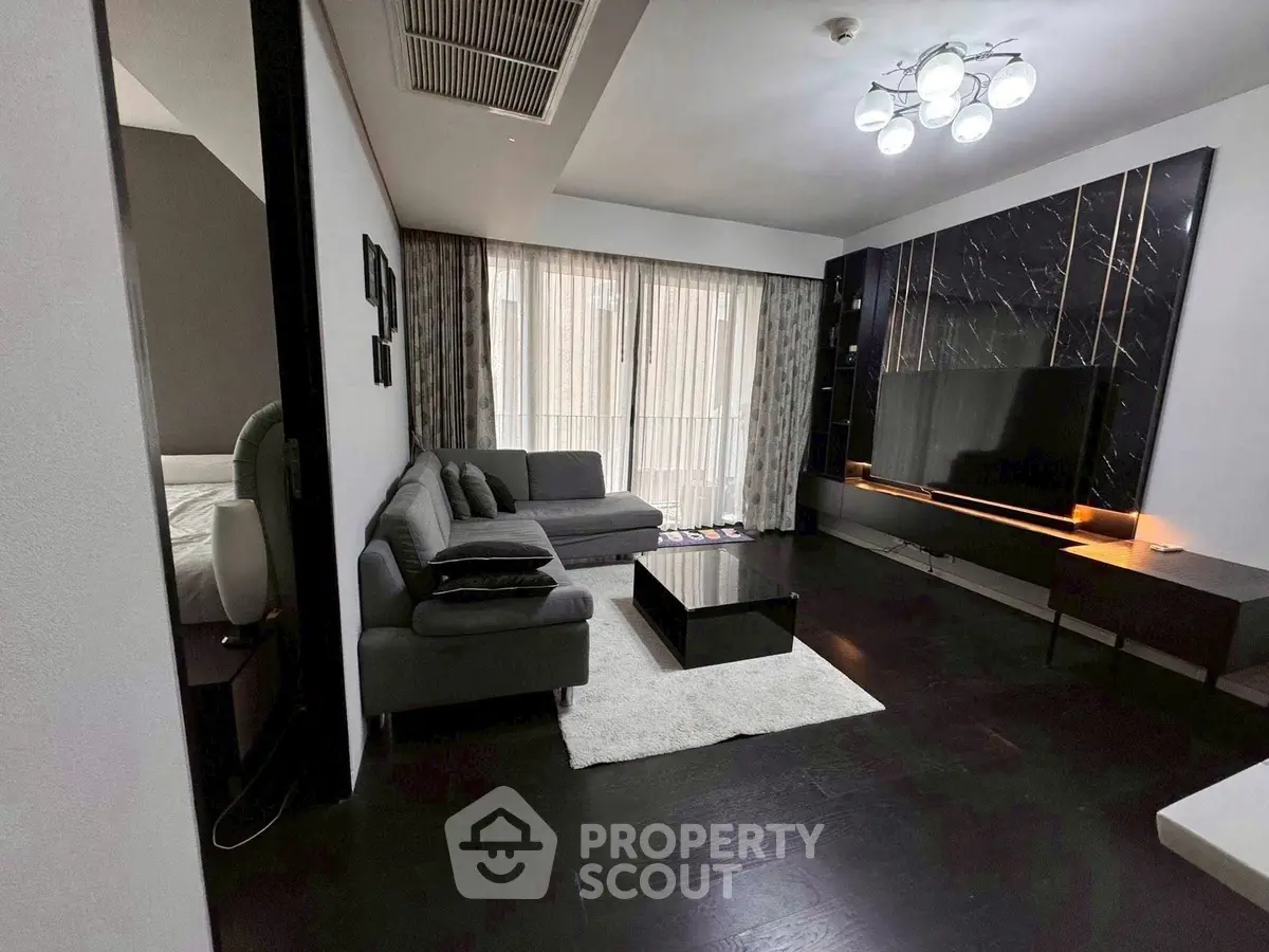 Modern living room with sleek design and large TV, featuring dark wood flooring and stylish lighting.