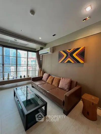Stylish living room with modern decor and city view, featuring a leather sofa and glass coffee table.