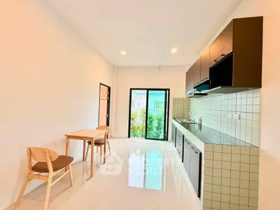 Modern kitchen with sleek cabinetry and dining area, featuring a bright open layout and garden view.