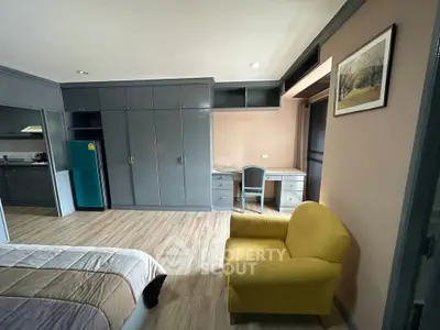 Spacious bedroom with modern furniture and cozy yellow armchair