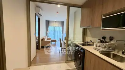Modern open-layout kitchen with sleek appliances and view into cozy living area.