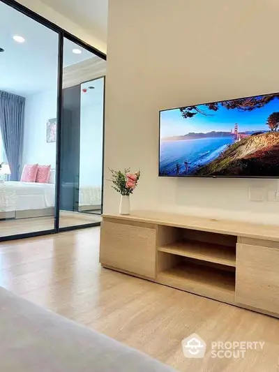 Modern living room with sleek TV and view into stylish bedroom