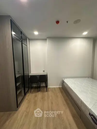 Modern bedroom with minimalist design, featuring a bed and sleek wardrobe in a cozy setting.
