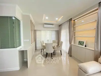 Elegant living room with modern decor and natural light, featuring a cozy dining area and stylish shelving.