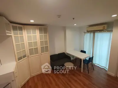 Cozy living room with wooden flooring, modern furniture, and natural light from large windows.