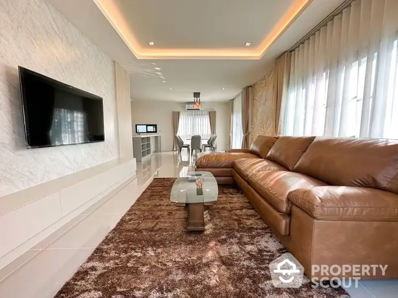 Luxurious living room with plush leather sofa, elegant marble walls, and modern lighting, seamlessly connected to a chic dining area.