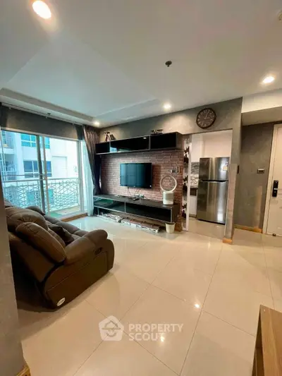 Modern living room with sleek design, featuring a large TV, comfortable seating, and a balcony view.