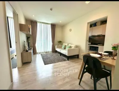 Modern living room with open kitchen, stylish decor, and natural light.