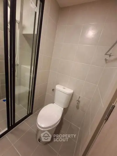 Modern bathroom with sleek design and tiled walls, featuring a shower and toilet.