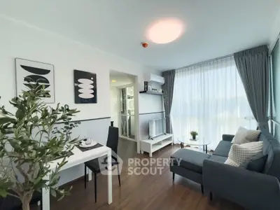 Modern living room with stylish decor and natural light, featuring a cozy sofa and dining area.