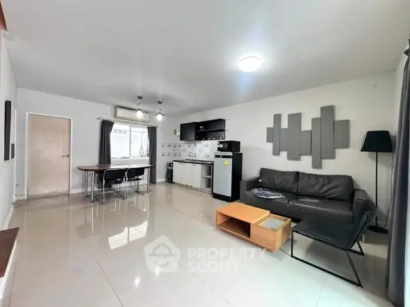 Spacious modern living room with open kitchen, sleek furniture, and ample natural light.