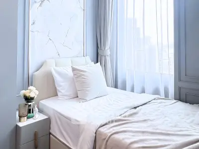 Luxurious bedroom with elegant decor and city view, featuring plush bedding and stylish nightstand.