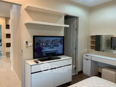 Modern bedroom with TV and sleek white furniture, showcasing a stylish and functional interior design.