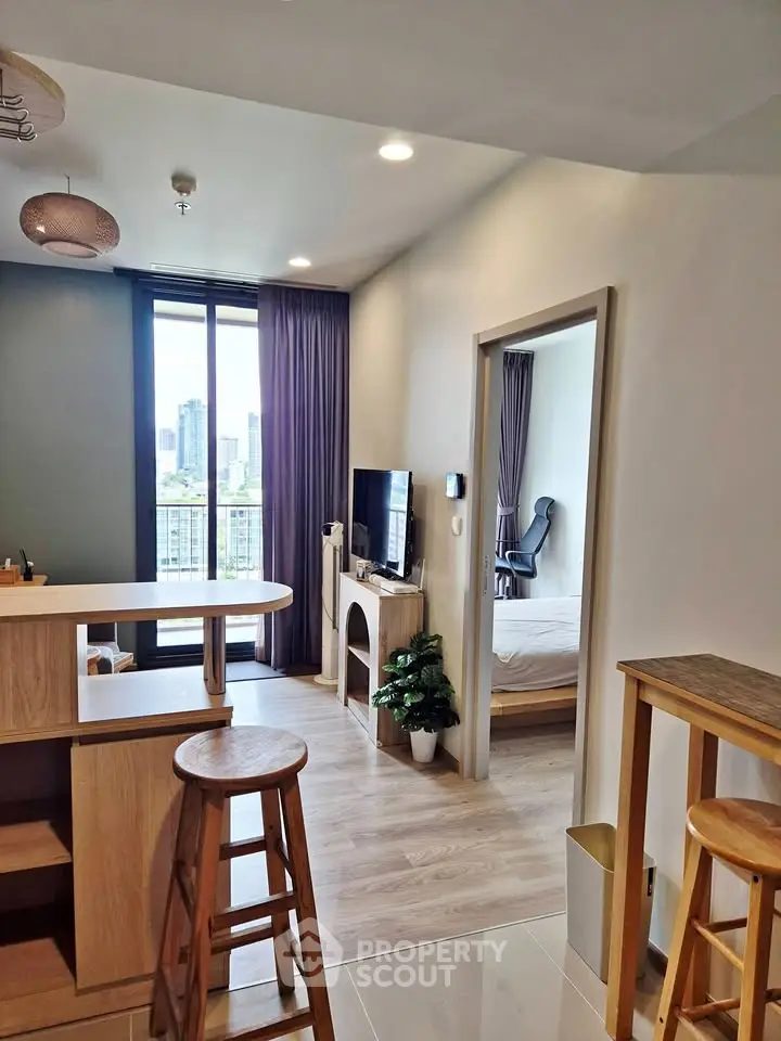 Modern apartment interior with open layout, wooden furniture, and city view from balcony.