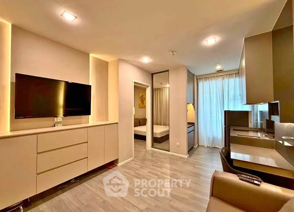 Modern living room with sleek design and open layout, featuring a large TV and stylish furniture.