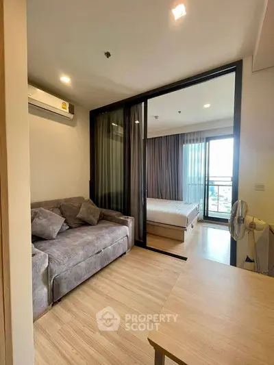 Modern apartment with cozy living room and bedroom, featuring large windows and stylish decor.
