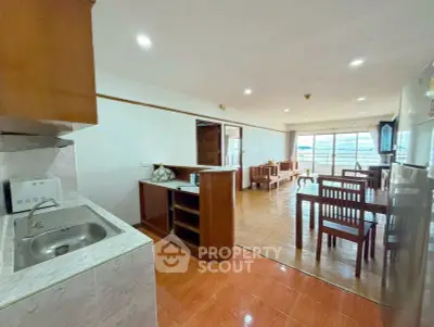 Spacious open-plan living and dining area with kitchen, featuring wooden flooring and ample natural light.