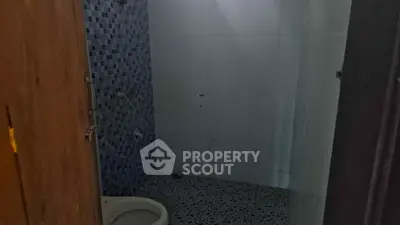 Compact bathroom with tiled walls and floor, featuring a toilet and shower area.