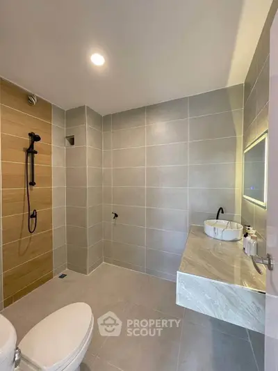 Modern bathroom with sleek design, featuring a wall-mounted sink and spacious shower area.