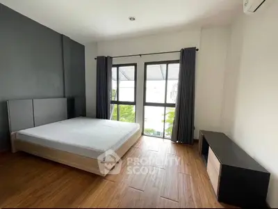 Spacious bedroom with large window and modern furnishings