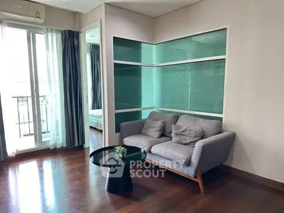 Modern living room with sleek sofa and glass partition, featuring hardwood floors and natural light.