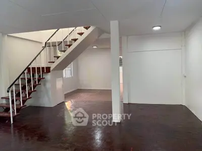 Spacious open-plan living area with wooden staircase and natural light.
