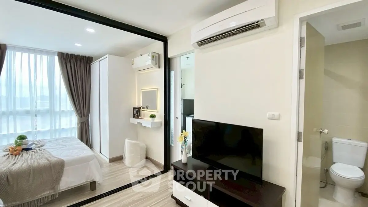 Modern apartment interior with bedroom and living area, featuring sleek design and natural light.