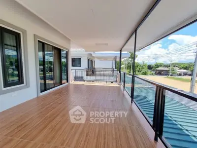 Spacious balcony with modern glass railing and scenic view, perfect for relaxation.