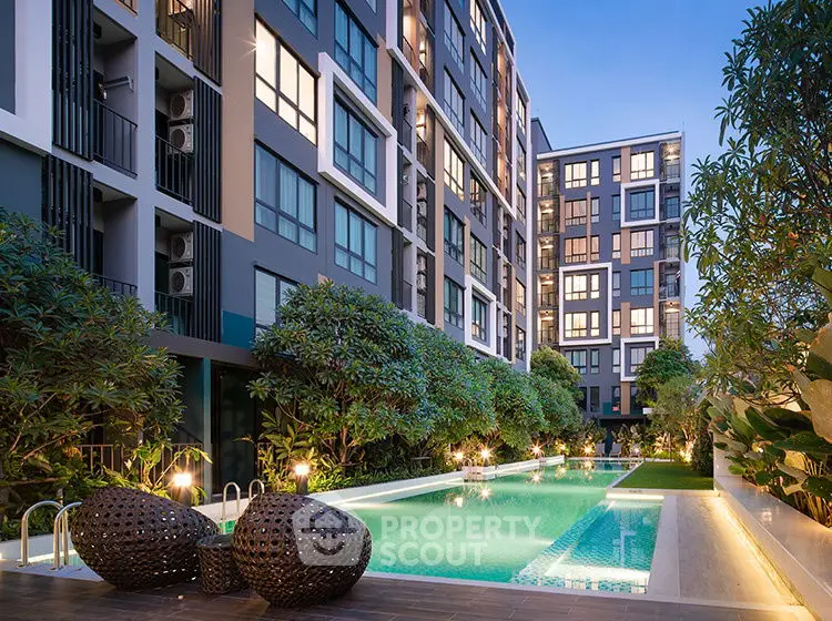 Luxurious apartment complex with stunning pool and lush greenery at dusk.