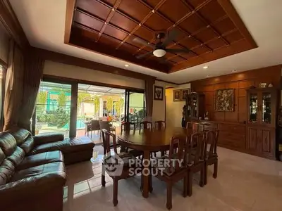 Elegant living room with wooden ceiling and pool view, featuring classic furniture and ample natural light.