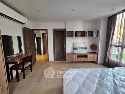 Spacious modern bedroom with wooden flooring and stylish furniture in a bright apartment.