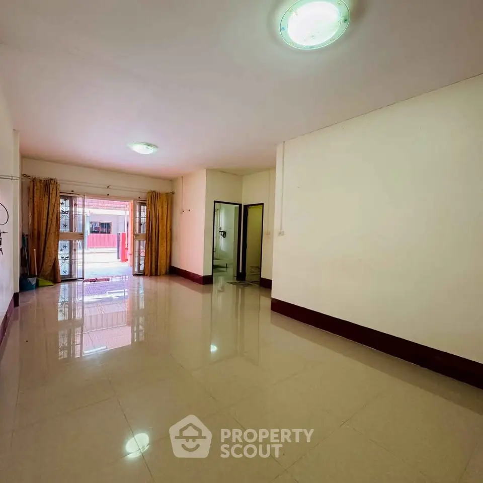 Spacious living room with glossy tiled floors and large windows for natural light.
