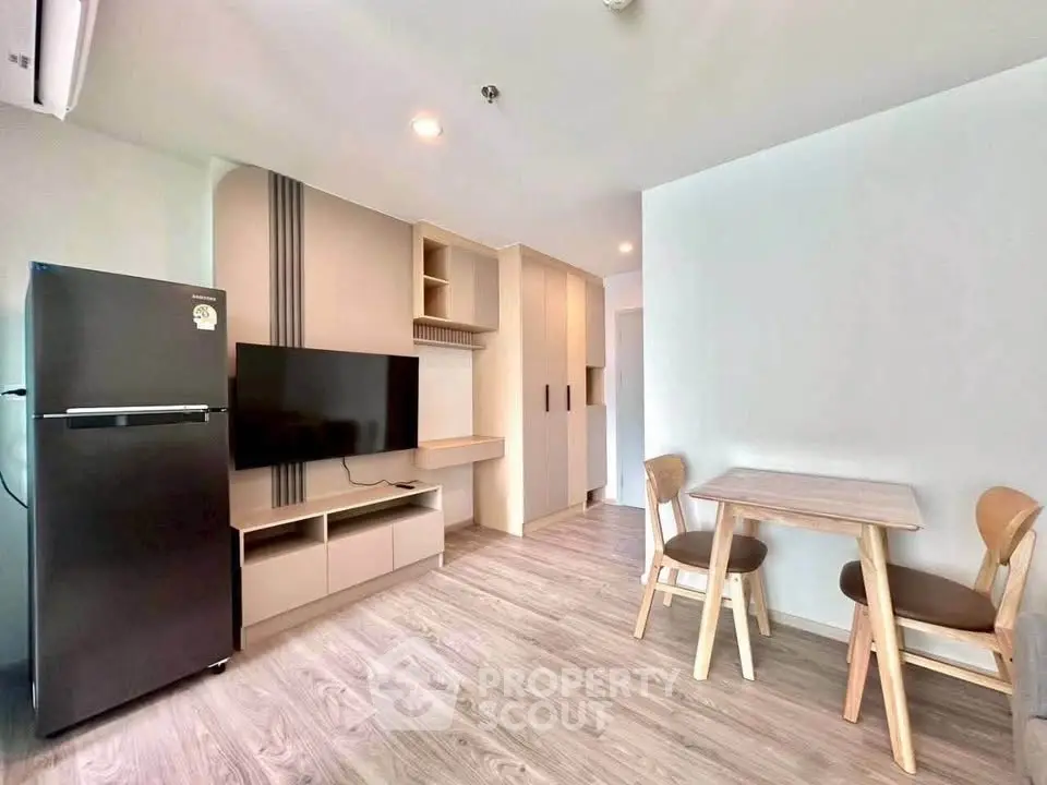 Modern living room with sleek furniture and open layout, featuring a TV and dining area.