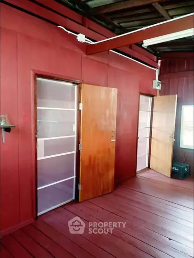 Charming wooden interior with vibrant red walls and wooden doors, perfect for a cozy retreat.