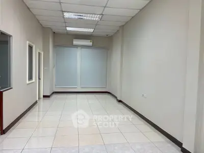 Spacious empty room with tiled floor and large windows, ideal for office or studio setup.