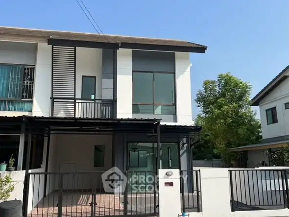 Modern two-story house with sleek design and spacious driveway in a suburban neighborhood.