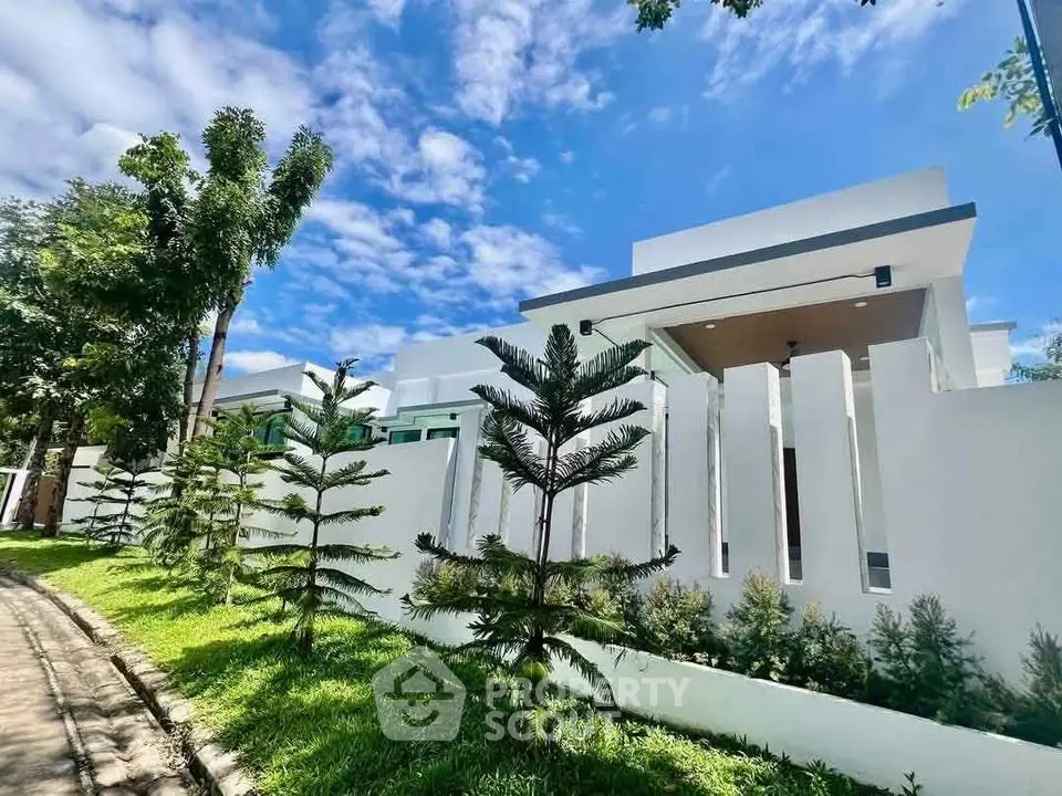 Modern architectural home with sleek white facade and lush greenery