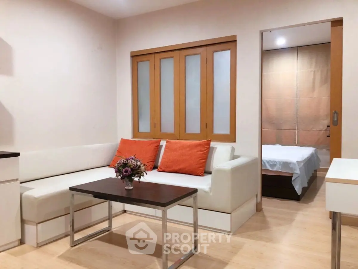 Modern living room with cozy sofa and bedroom view in open layout apartment.