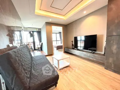 Modern living room with sleek design and large TV, featuring stylish lighting and cozy seating.