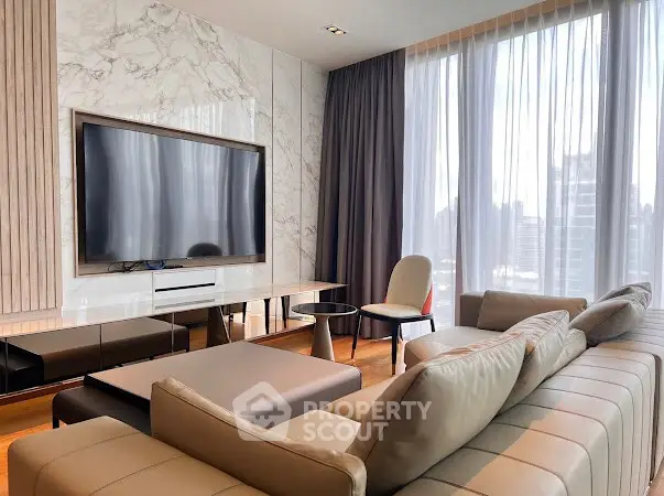 Luxurious modern living room with large TV and elegant furniture, featuring floor-to-ceiling windows.