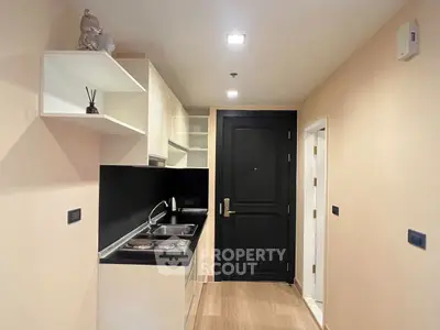 Modern compact kitchen with sleek black countertops and open shelving in a cozy apartment.