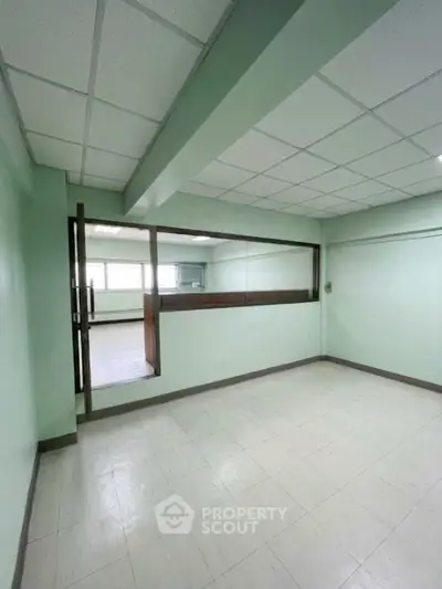 Spacious empty room with large window and tiled floor, ideal for office or studio setup.